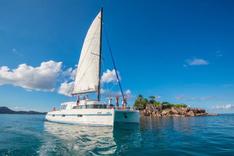 Catamaran Catlante sous voile près d'un îlot de granit aux Seychelles