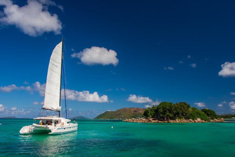 Catamaran sous voile dans le lagon, face à un îlot des Seychelles