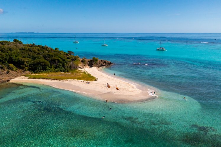Vue aérienne d'une langue de sable bordée d'eaux turquoise aux Grenadines, voiliers au mouillage