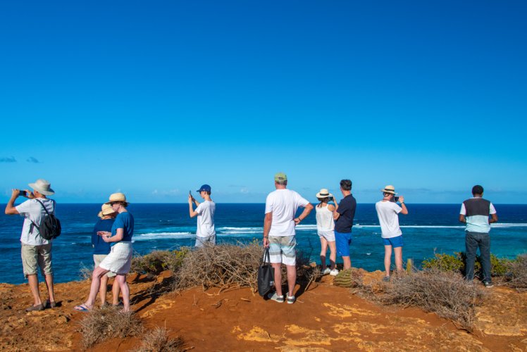 Groupe de voyageurs en escale à terre, face à l'océan, lors d'une croisière en catamaran