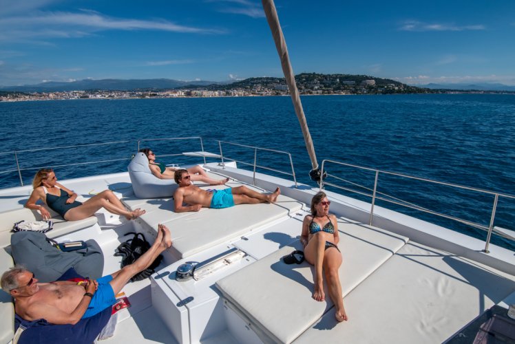 Passagers installés sur le pont avant d'un catamaran Catlante au mouillage